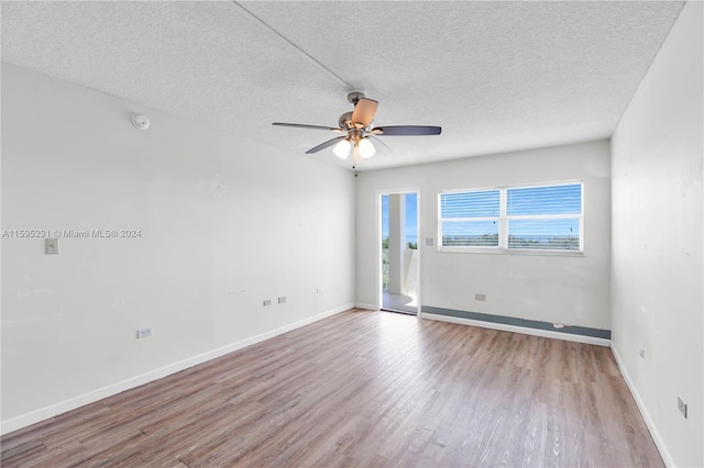 unfurnished room featuring ceiling fan, wood finished floors, baseboards, and a textured ceiling