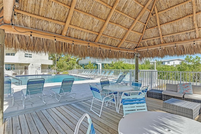 deck with a gazebo, a community pool, and fence