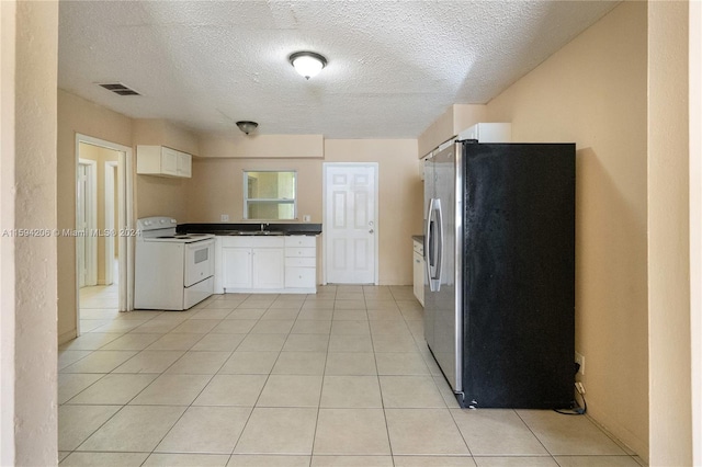 kitchen featuring sink, white electric stove, stainless steel refrigerator with ice dispenser, light tile patterned floors, and white cabinetry