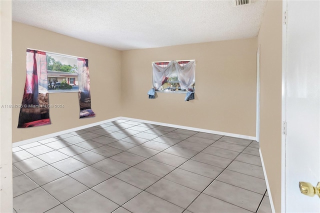 tiled empty room with a textured ceiling