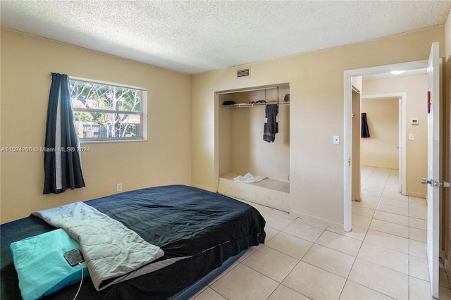 bedroom with light tile patterned floors, a textured ceiling, and a closet