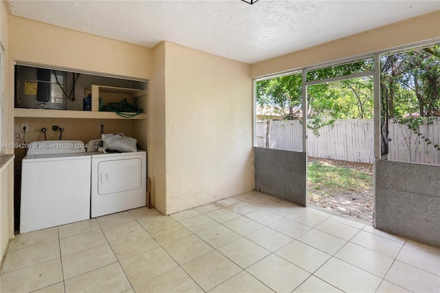 clothes washing area featuring washing machine and clothes dryer, light tile patterned floors, and a textured ceiling