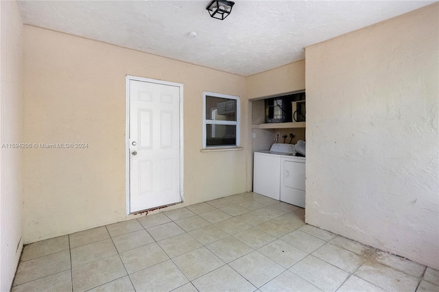 laundry area with washing machine and clothes dryer and light tile patterned floors