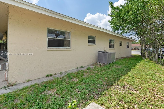 view of side of property featuring central air condition unit and a yard