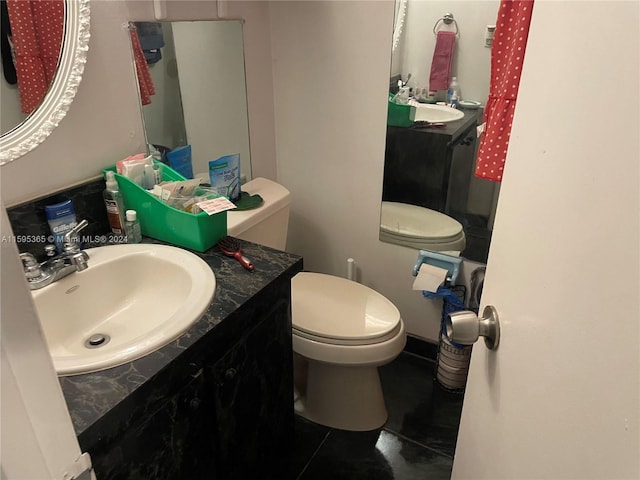 bathroom with toilet, vanity, and tile patterned flooring