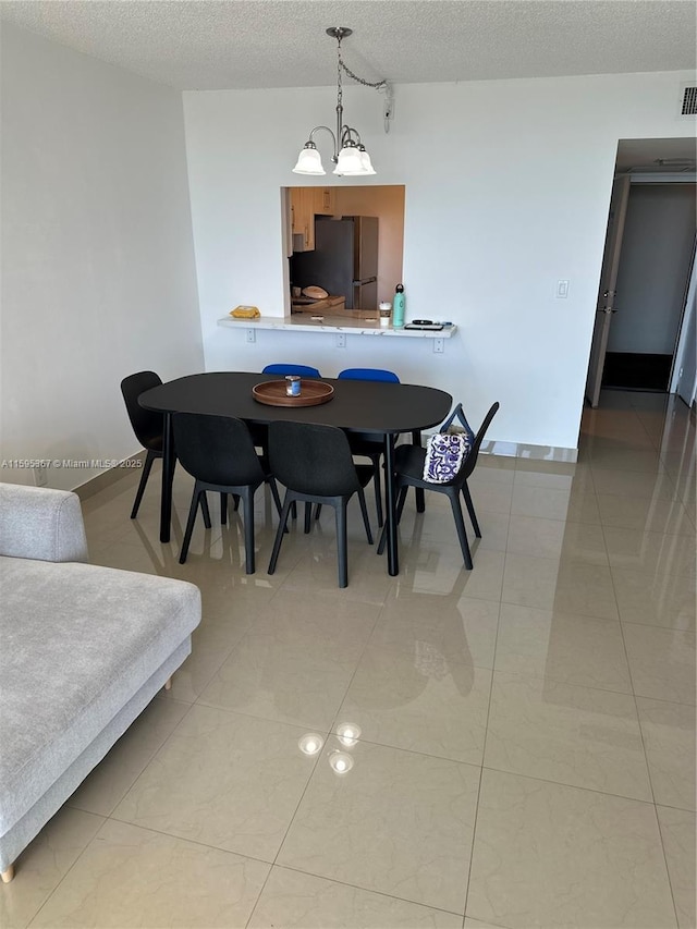 dining space with light tile patterned floors, a textured ceiling, and an inviting chandelier