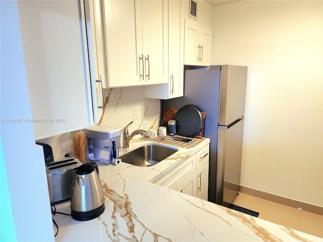 kitchen featuring light tile patterned flooring, white cabinetry, light stone counters, and sink