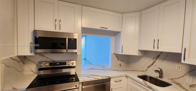 kitchen featuring sink, decorative backsplash, light stone counters, white cabinetry, and stainless steel appliances