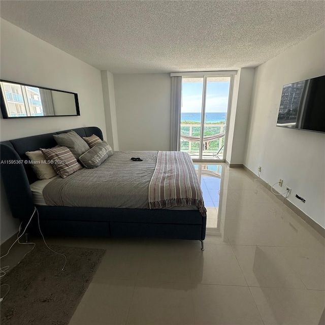 tiled bedroom with a textured ceiling, access to outside, and a wall of windows