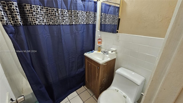 bathroom with tile patterned floors, vanity, tile walls, and toilet