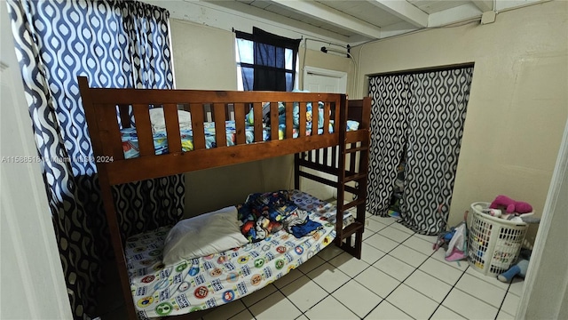 bedroom with tile patterned flooring and beamed ceiling