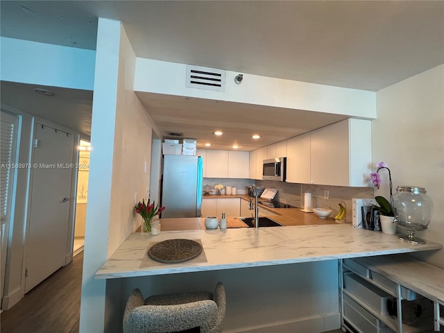 kitchen featuring a peninsula, appliances with stainless steel finishes, visible vents, and white cabinetry