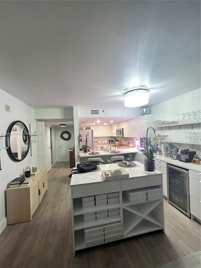 kitchen with wine cooler, open shelves, light countertops, white cabinets, and wood finished floors