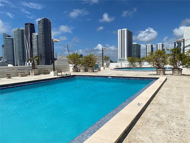 community pool with a view of city and a patio