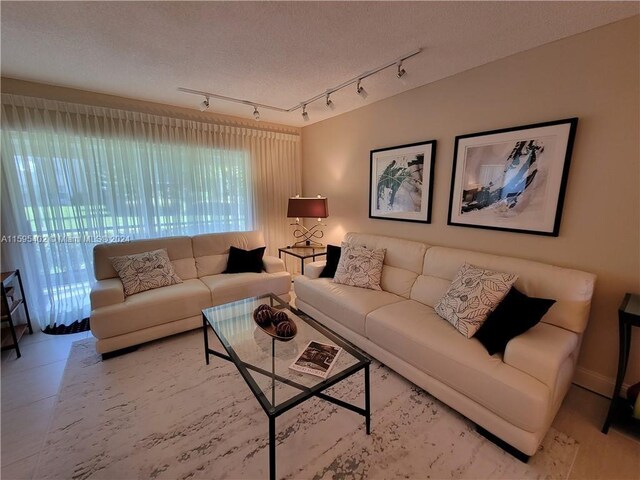 tiled living room featuring track lighting and a textured ceiling