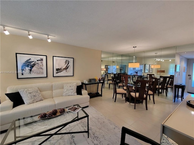 tiled living room featuring a textured ceiling, an inviting chandelier, and rail lighting