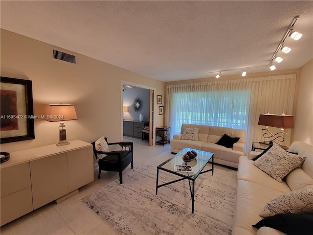 living room with a textured ceiling and rail lighting