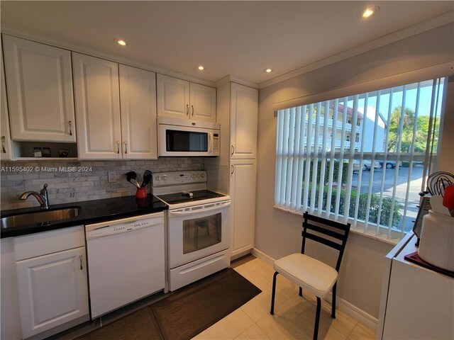 kitchen with white cabinetry, white appliances, sink, tasteful backsplash, and light tile floors