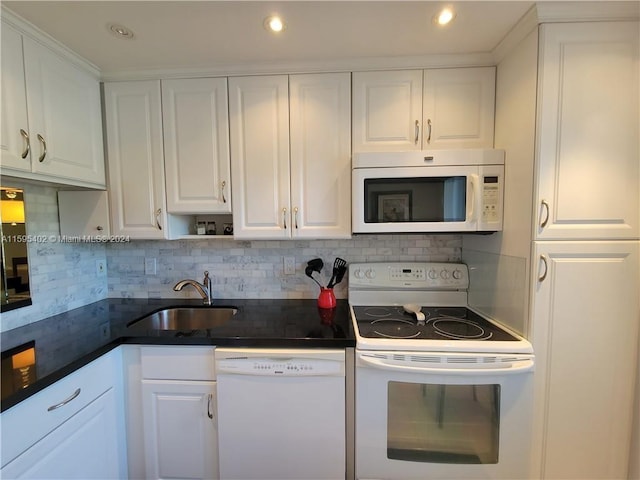 kitchen featuring white appliances, dark countertops, a sink, and white cabinets