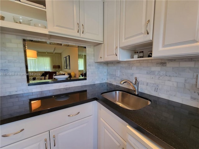 kitchen with dishwasher, dark stone countertops, backsplash, sink, and white cabinetry