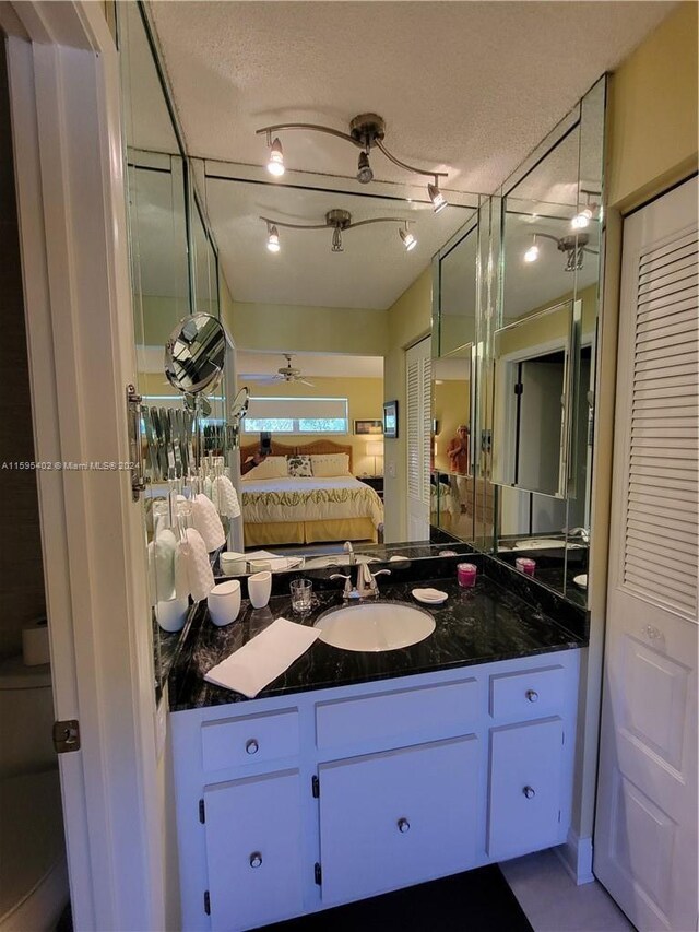 bathroom with vanity, ceiling fan, and a textured ceiling