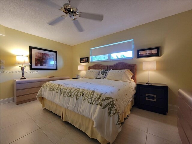 tiled bedroom with ceiling fan and a textured ceiling