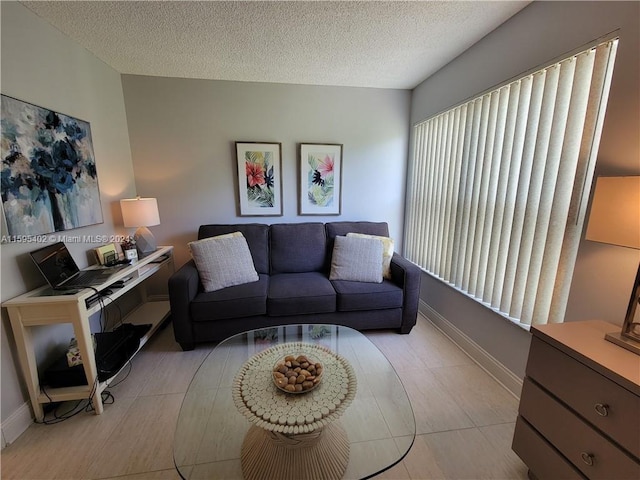 living room featuring light tile patterned flooring, a textured ceiling, and baseboards