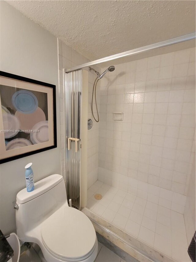 bathroom with tiled shower, a textured ceiling, and toilet