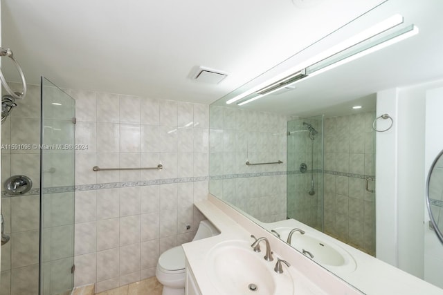 bathroom with toilet, vanity, tile walls, tile patterned floors, and an enclosed shower