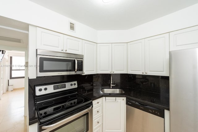 kitchen with tasteful backsplash, sink, stainless steel appliances, and white cabinetry