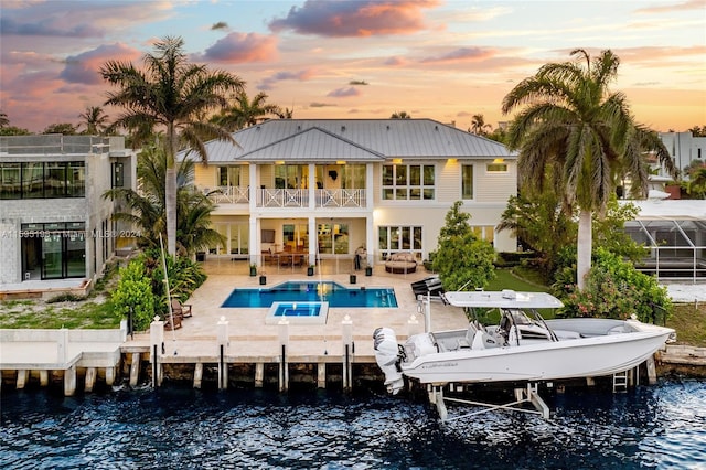 back house at dusk with a patio area, an outdoor living space, a balcony, and a water view