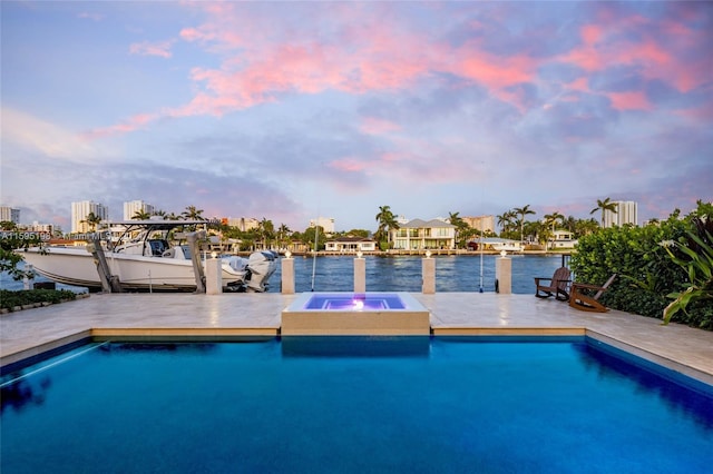 pool at dusk with a water view, an in ground hot tub, and a dock