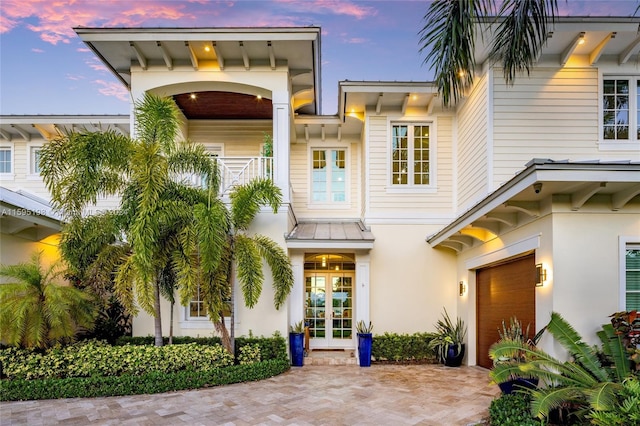 back house at dusk featuring a balcony and french doors