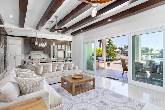 living room with beamed ceiling, ceiling fan, a barn door, and sink