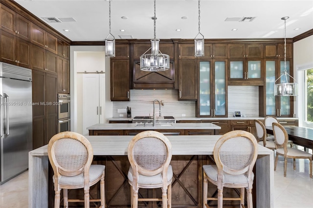 kitchen featuring a center island with sink, decorative light fixtures, decorative backsplash, and appliances with stainless steel finishes