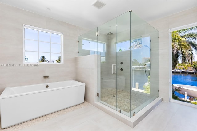 bathroom featuring tile patterned floors, separate shower and tub, and tile walls