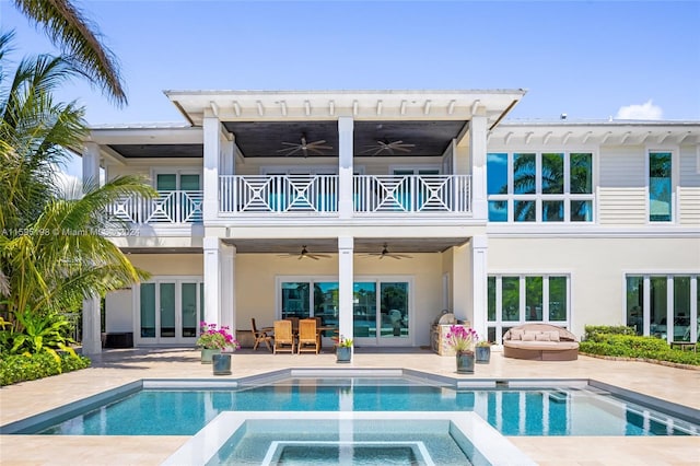 rear view of house featuring a balcony, ceiling fan, and a pool with hot tub