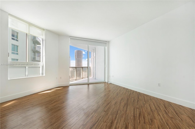 empty room with floor to ceiling windows and wood-type flooring