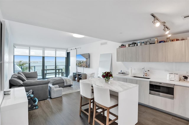 kitchen with a center island, oven, sink, dark hardwood / wood-style flooring, and a kitchen bar