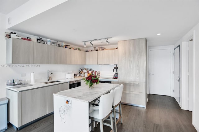 kitchen with a kitchen bar, light stone counters, dark wood-type flooring, sink, and a center island