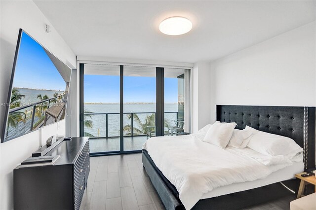 bedroom with access to outside, floor to ceiling windows, and light hardwood / wood-style floors