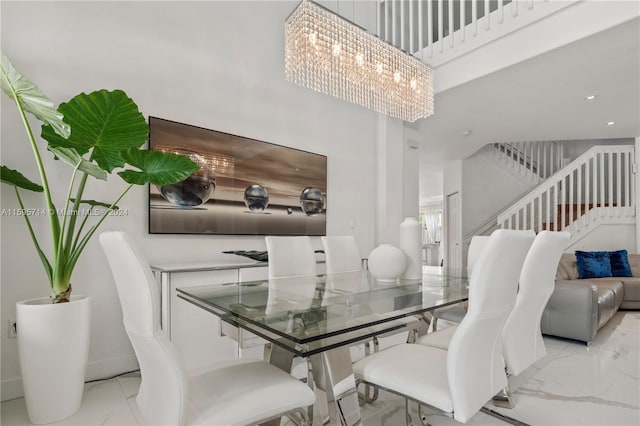dining space featuring a high ceiling, marble finish floor, and stairs