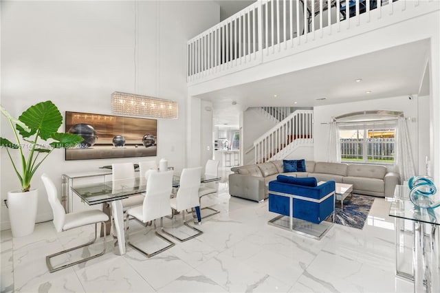dining area with a high ceiling, marble finish floor, and stairs