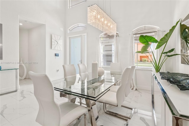dining room with marble finish floor, a high ceiling, and baseboards