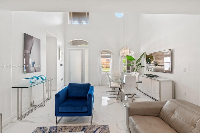 living room with a towering ceiling, baseboards, and marble finish floor