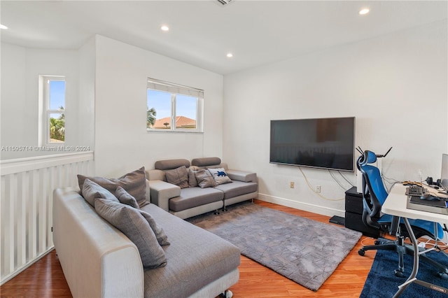 living area with baseboards, wood finished floors, a wealth of natural light, and recessed lighting