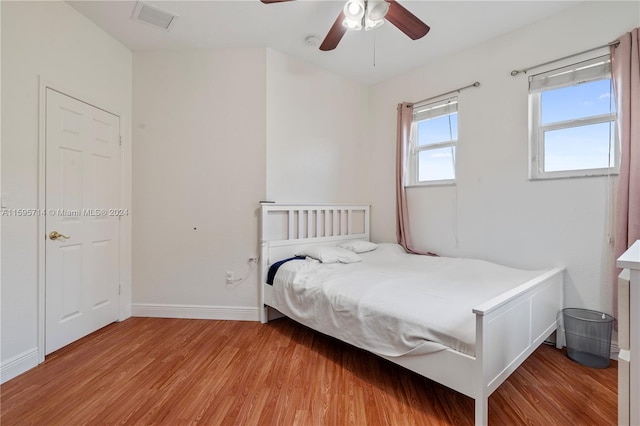 bedroom with light wood-style flooring, visible vents, baseboards, and ceiling fan
