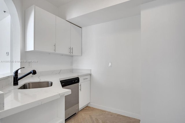 kitchen with light stone counters, stainless steel dishwasher, white cabinets, sink, and light parquet flooring