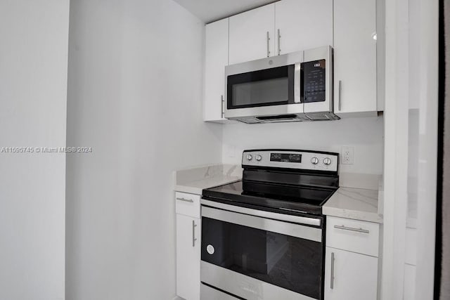 kitchen featuring light stone counters, white cabinets, and appliances with stainless steel finishes