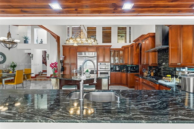 kitchen featuring appliances with stainless steel finishes, sink, wooden ceiling, wall chimney exhaust hood, and dark stone counters